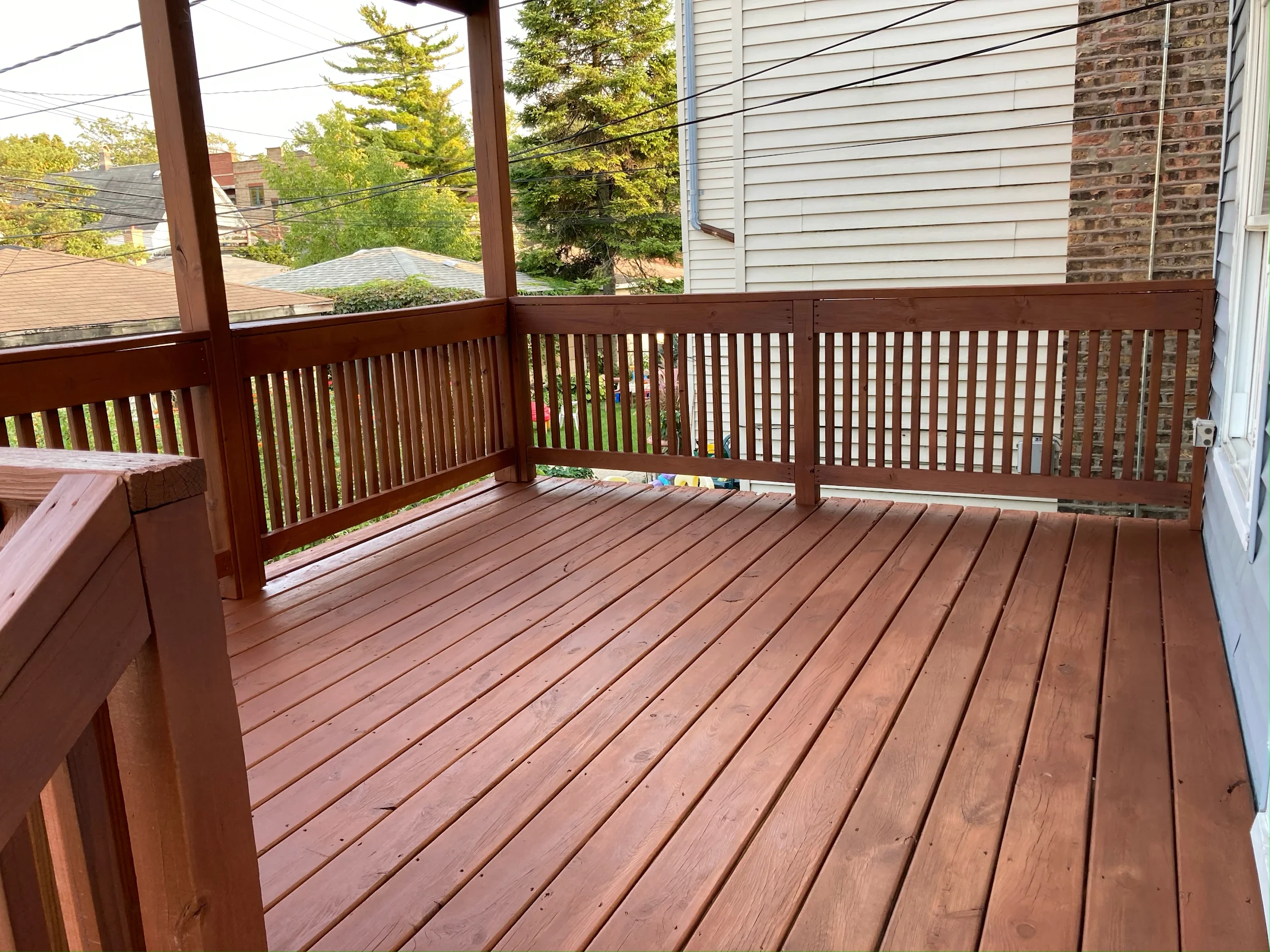 Clean deck after pressure washing in Champaign County — bright stained wood boards and dark metal railing